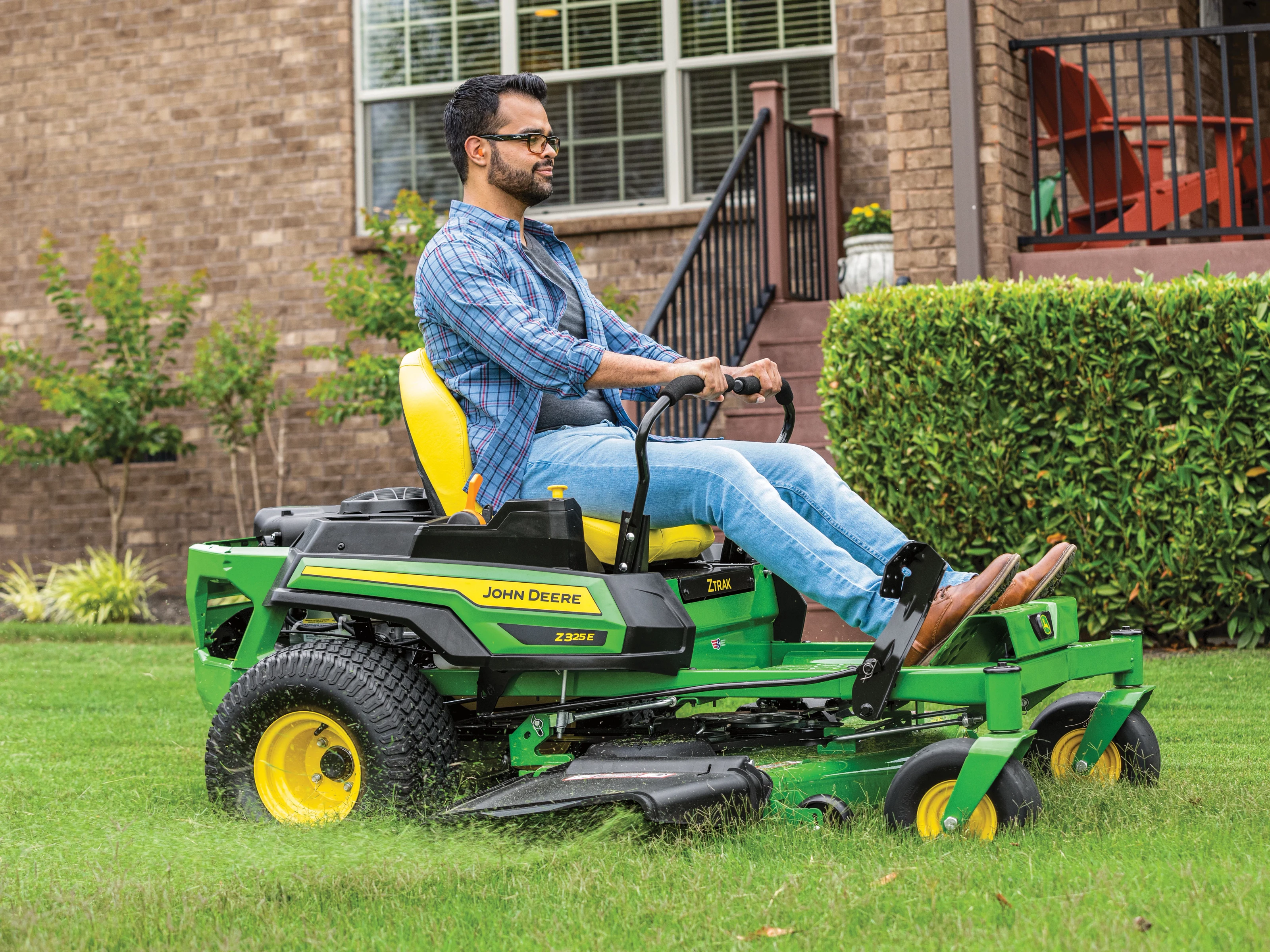Homeowner mowing a residential lawn on a John Deere ZTrak zero-turn mower